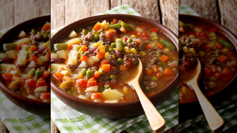 hamburger soup with ground beef and mix of vegetables close-up in a bowl on the table, mirrored image