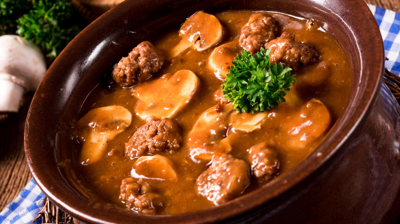 close up of mock turtle soup with mushrooms in brown bowl