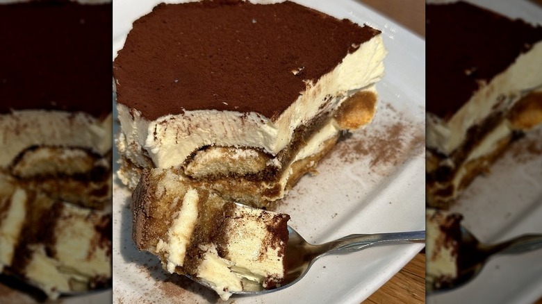A slice of Olive Garden tiramisu on a white plate with a spoon