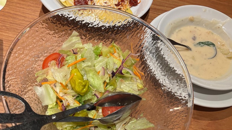 Glass bowl with a salad in it with a white bowl of soup
