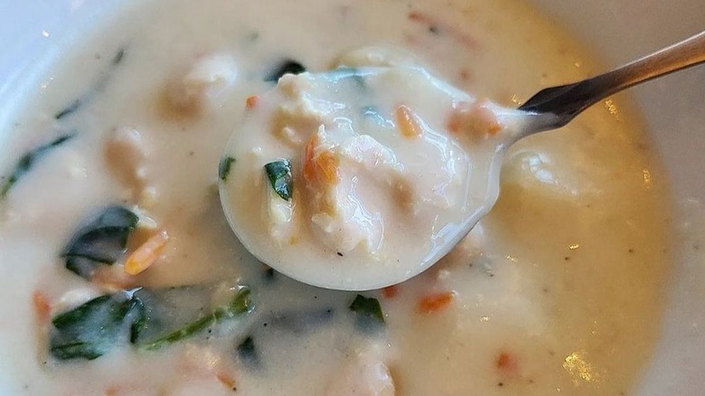 Chicken gnocchi soup from Olive Garden in a white bowl with a spoon scooping it out