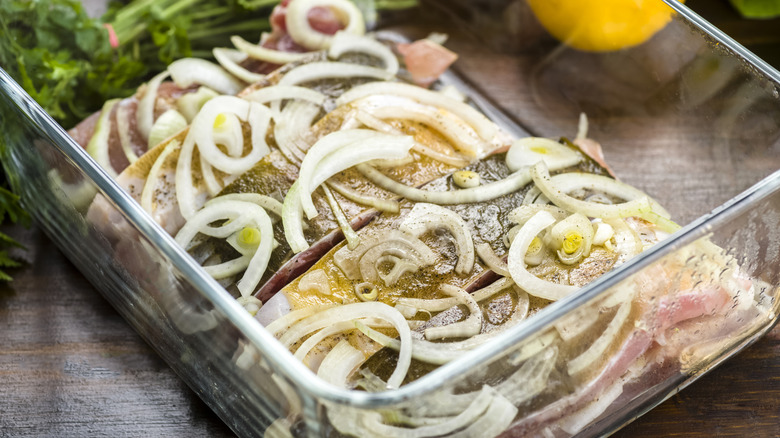 fish portions in marinade, covered with sliced onions