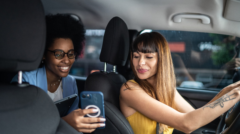 A passenger showing her phone to a driver