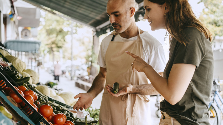 Two people choosing produce at an outdoor food market