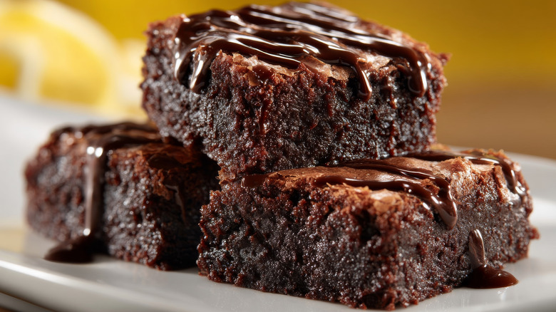 Three fudge chocolate brownies stacked on plate