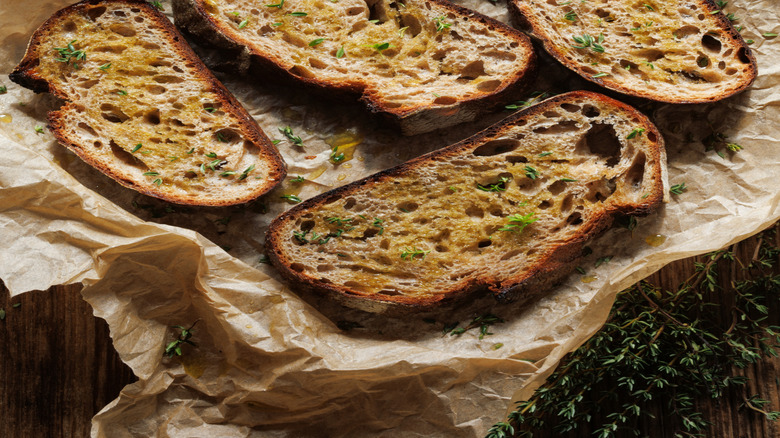 Sliced of sourdough topped with olive oil and fresh thyme