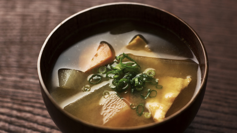 miso soup with vegetables and green onion in a wood bowl