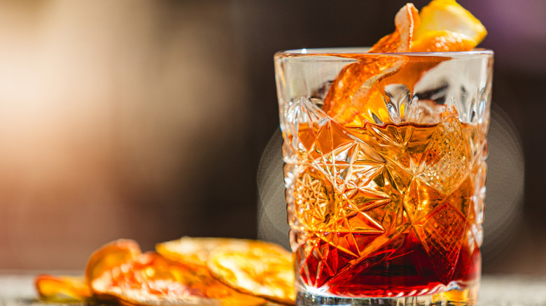 An old fashioned cocktail in a tumbler with an orange peel