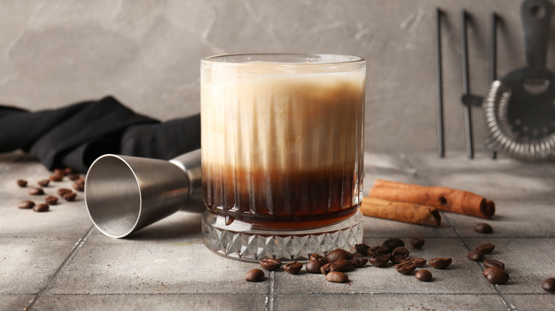 A classic white Russian in a tumbler with coffee beans around it
