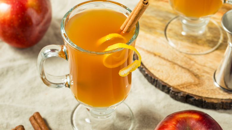A glass of hot toddy with cinnamon sticks and an orange twist