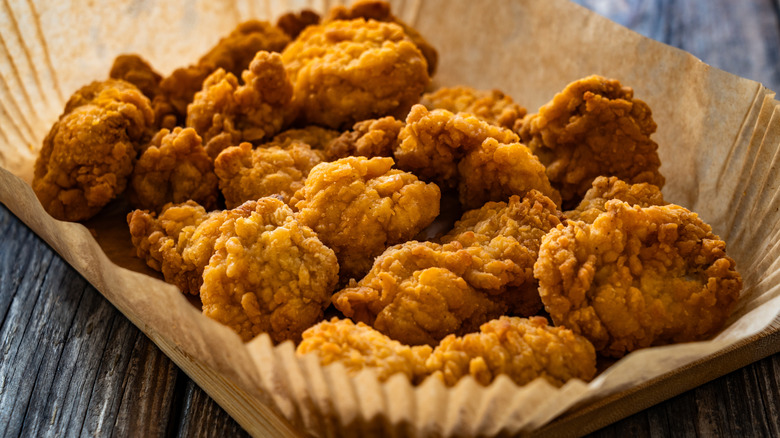 A plate of crispy fried golden nuggets inside a paper bowl