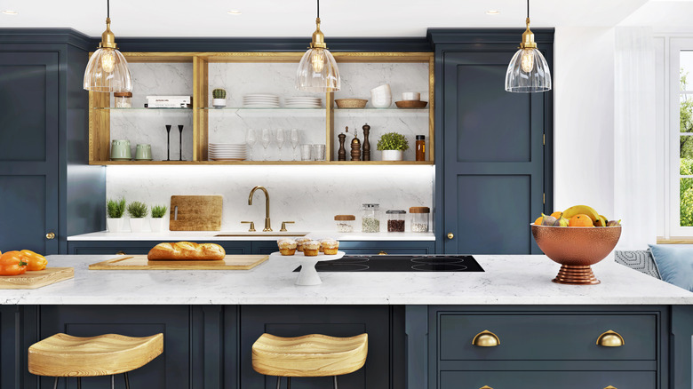 A statement bowl of fruit placed on marble kitchen island with dark cabinetry