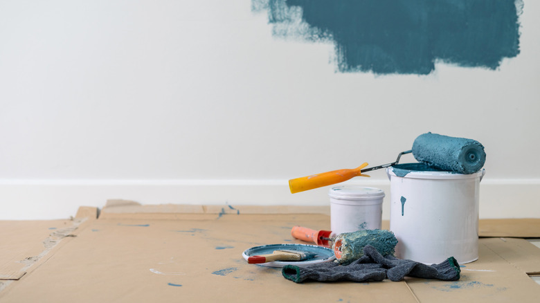 Close-up of paint roller, can and assorted tools placed on floor