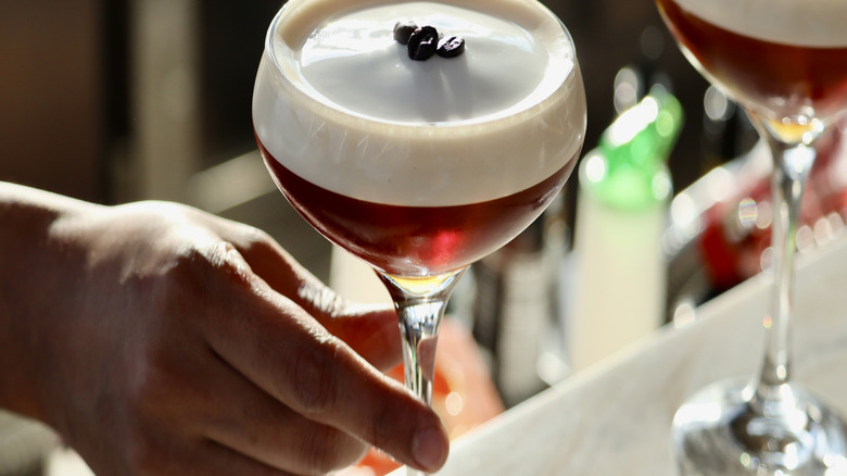 A hand reaching for an espresso martini
