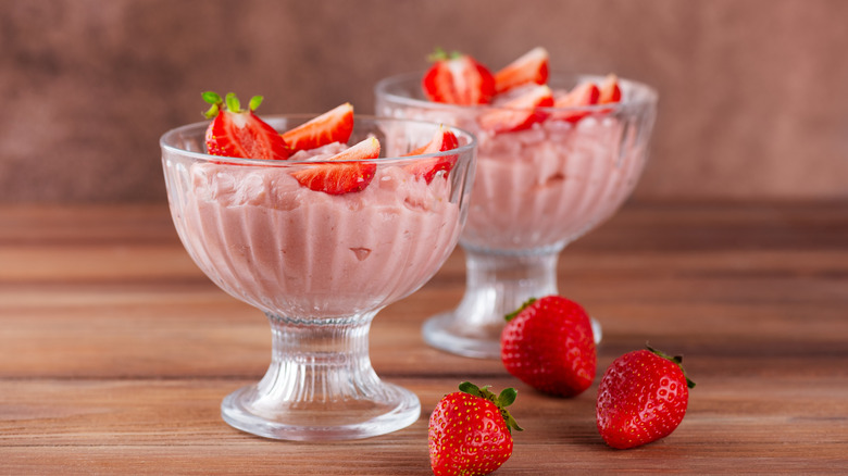 Strawberry mousse in two glass dessert bowls, topped with fresh strawberries