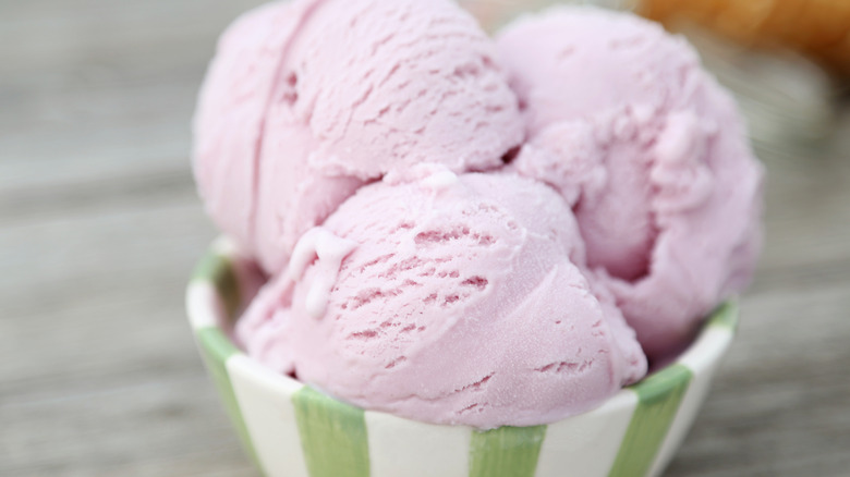 Scoops of pale pink ice cream in green striped bowl