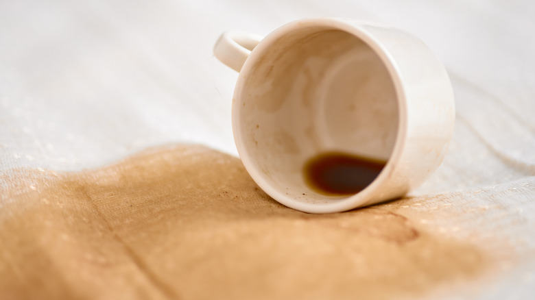 A white coffee mug spilling a stain on a white cloth