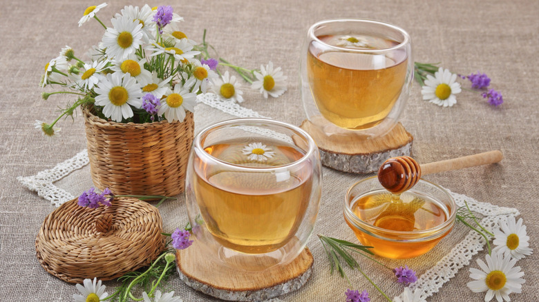 Tea with chamomile flowers, lavender, and raw honey on a doily
