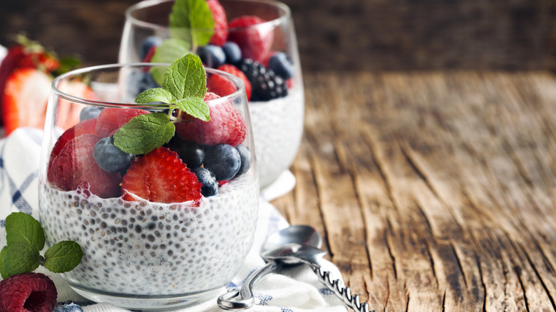 Two chia pudding cups with berries next to two spoons