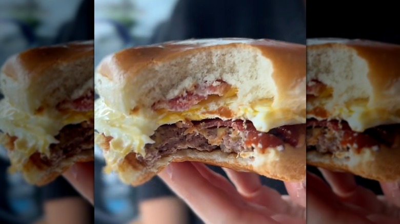 Hand holding a Breakfast Baconator with a hamburger patty that has a bite taken from it