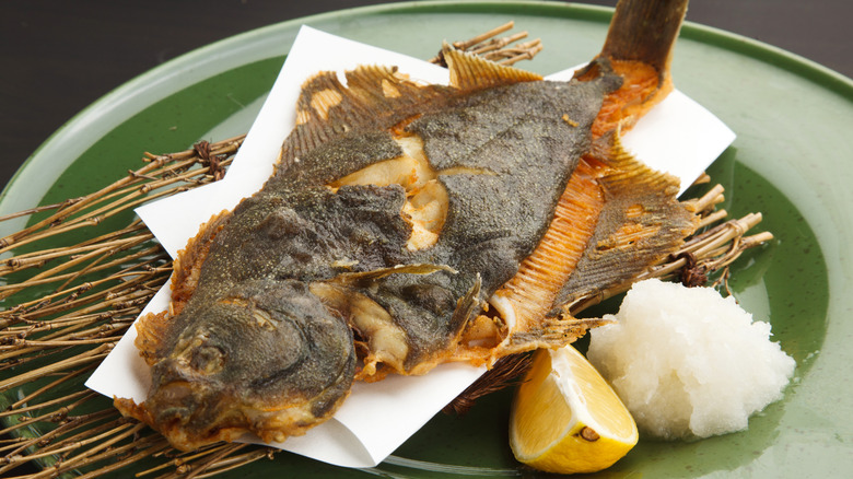 Salt-grilled whole flounder served on parchment and a lattice of fine twigs over a glossy green plate