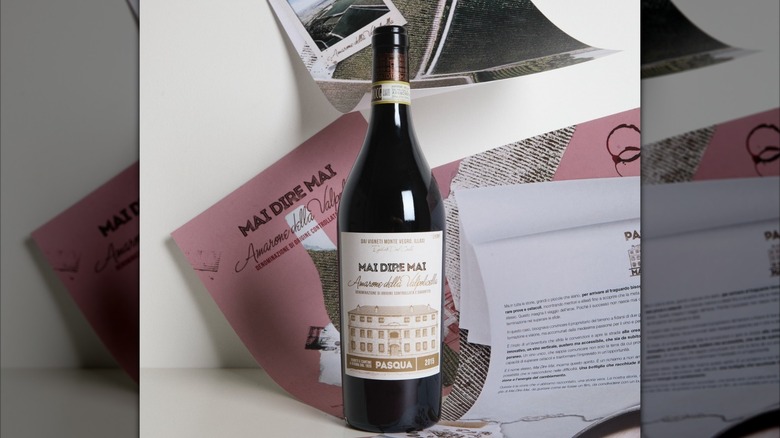 bottle of amarone wine stacked against a white wall surrounded by images and papers