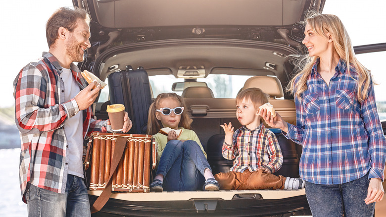 Family enjoying lunch beside their car