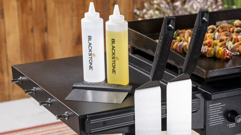 The Blackstone Griddle Kit organized on a grill accessory table next to a Blackstone griddle