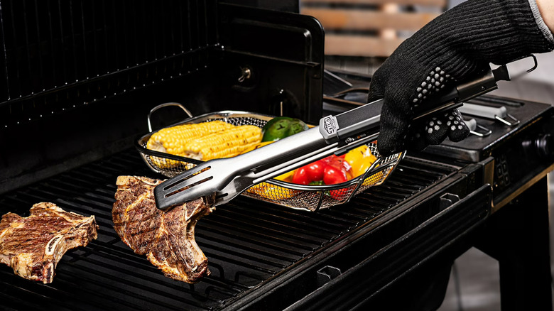Person wearing heat-resistant gloves picks up a steak using Expert Grill Tongs