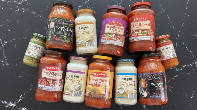Various Aldi pasta sauce jars on a dark countertop