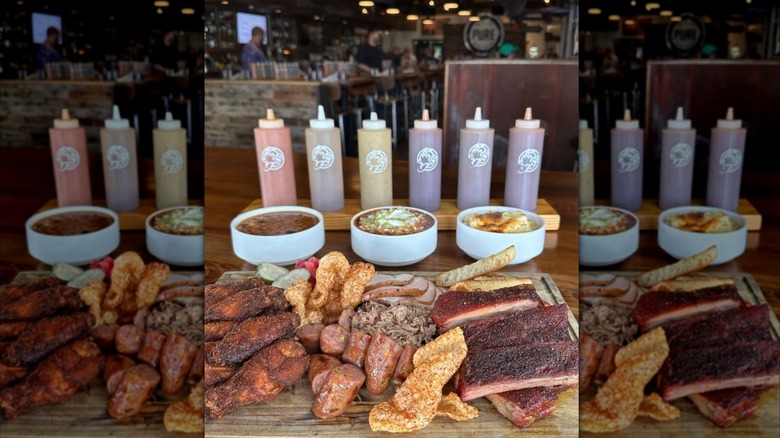 A plate of ribs from Home Team with bottles of barbecue sauces