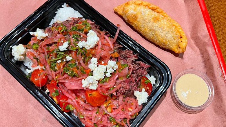 A barbacoa rice bowl from Palmira with an empanada on the side