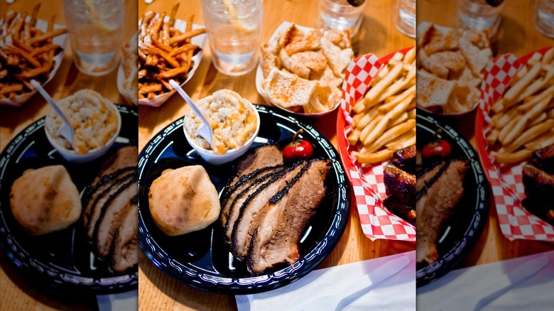 A black plate with briskest, a roll, and a cheesy side from The Smokin' Pig