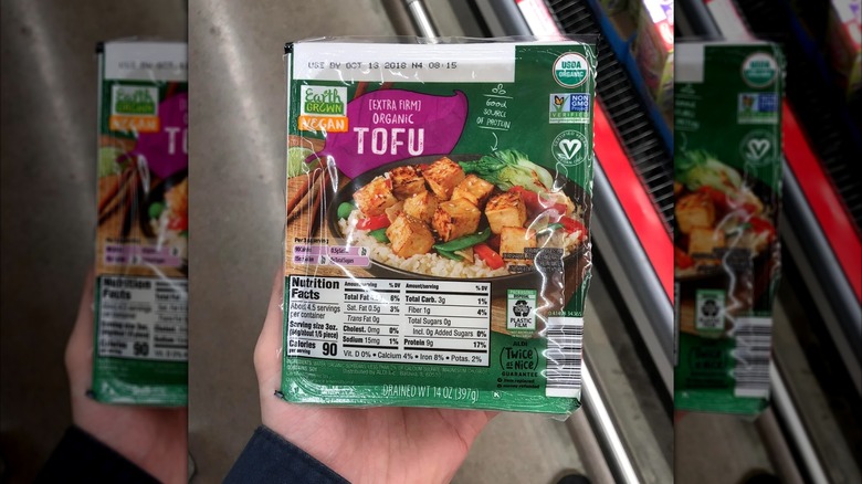 Hand holding package of extra firm tofu