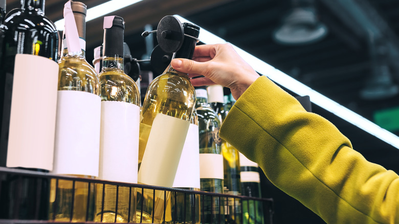 hand picking white wine bottle