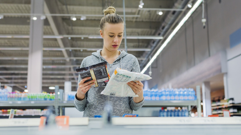 Customer choosing between two packages of frozen food
