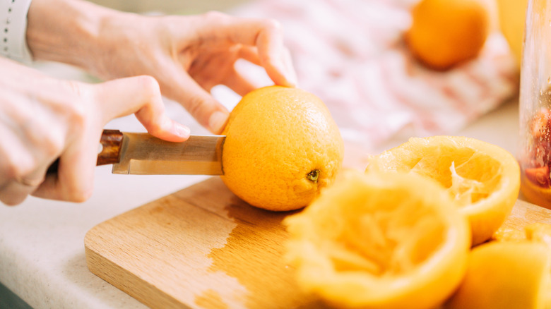 Woman cutting oranges and juicing them