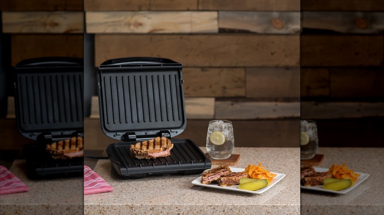 George Foreman 4-serving removable plate electric grill and panini press making panini on countertop with drink