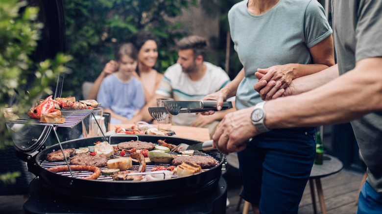 Cooking on a basic outdoor grill with family in background