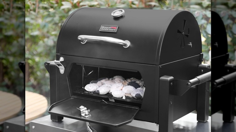 Royal Gourmet CD1519 portable charcoal grill outside with charcoal door open and hot coals inside