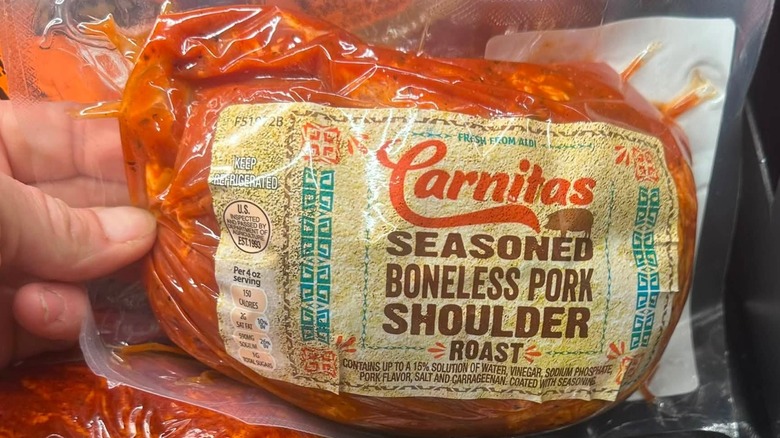 Hand holding package of Carnitas seasoned boneless pork shoulder roast