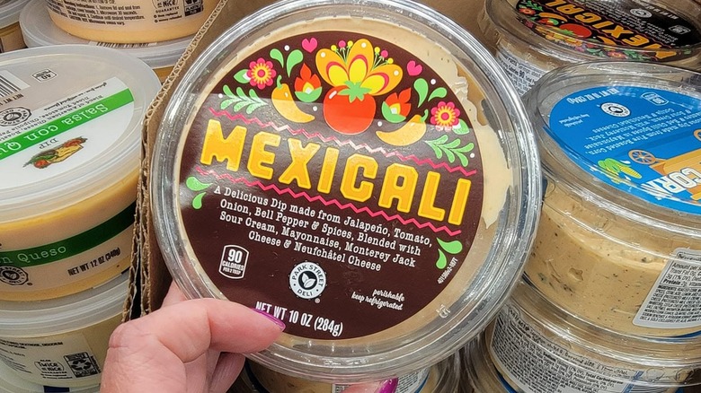 Hand holding Park Street Deli Mexicali dip near other Aldi dips
