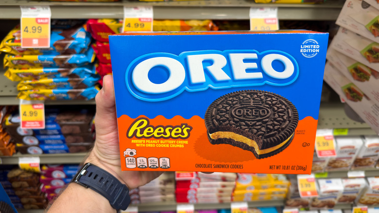Hand with a watch holding a box of Reese-flavored Oreos