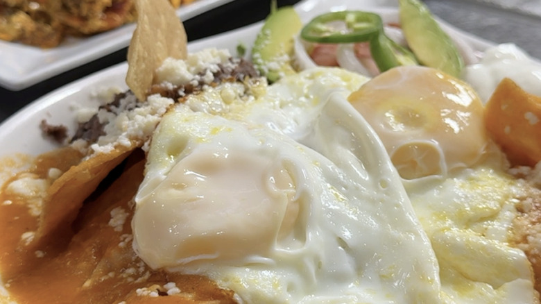 Eggs on tortilla chips on a white plate