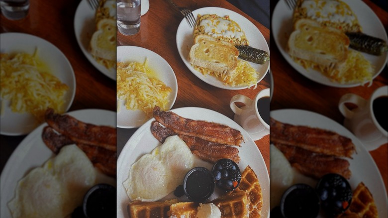 Breakfast foods on white plates on wooden table
