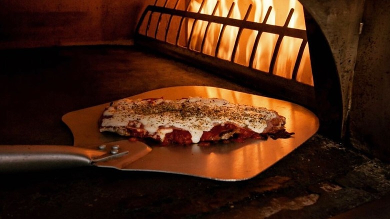 Milanesa Napolitana on pizza peel going into oven