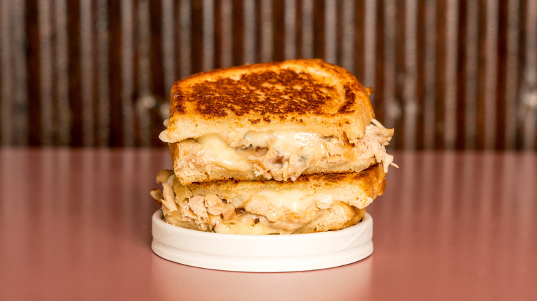 Stack of tuna melt halves on a white plate with a pinkish background and counter