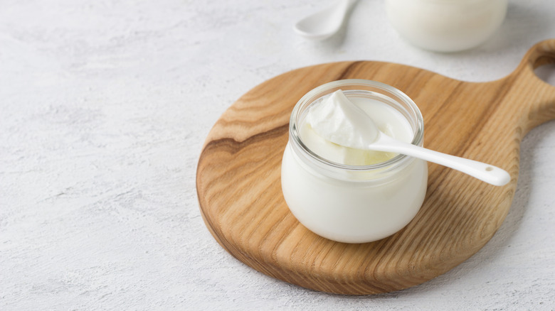 Yogurt in small glass jar on wooden board
