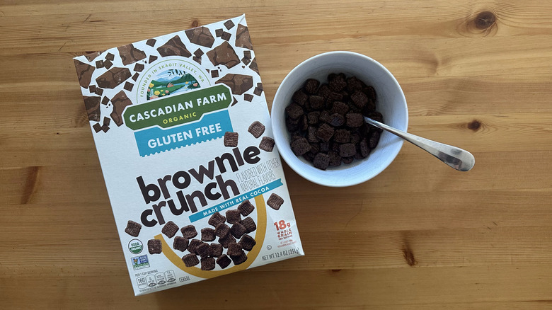 Gluten Free Brownie Crunch Cereal in a white bowl on table next to the cereal box