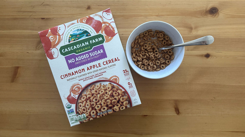 No Sugar Added Apple Cinnamon Cereal box and cereals served in a white bowl on a wooden table